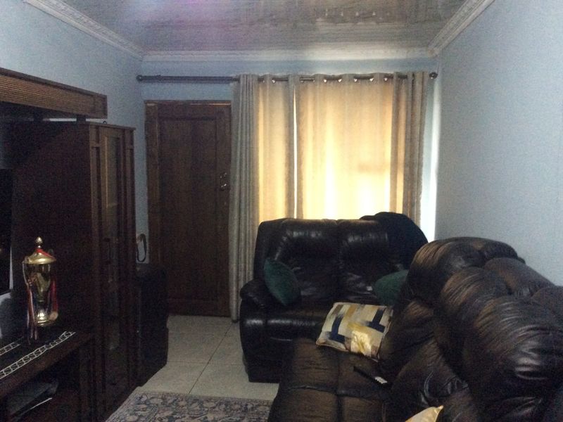 A living room featuring tiled flooring and crown molding, currently showing signs of ceiling water damage and wear.