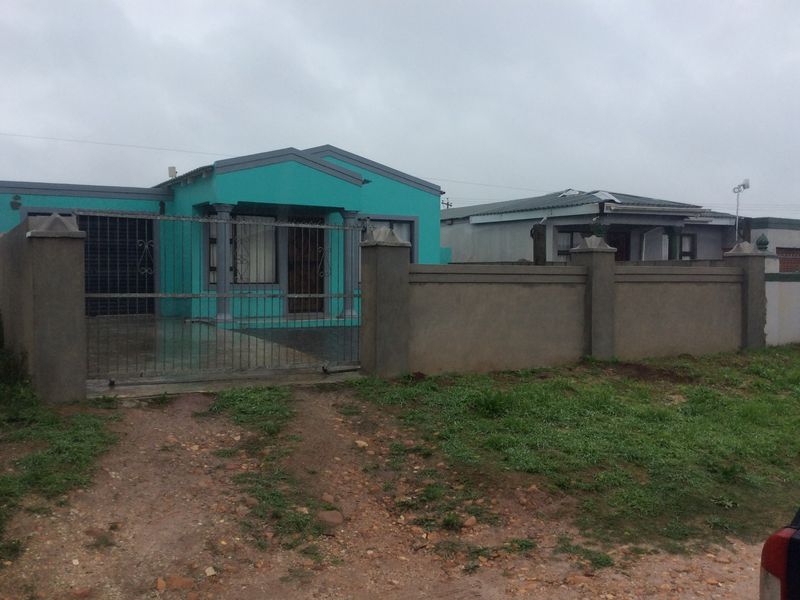 Front view of a detached house featuring a perimeter wall, metal security gate, and a concrete driveway.