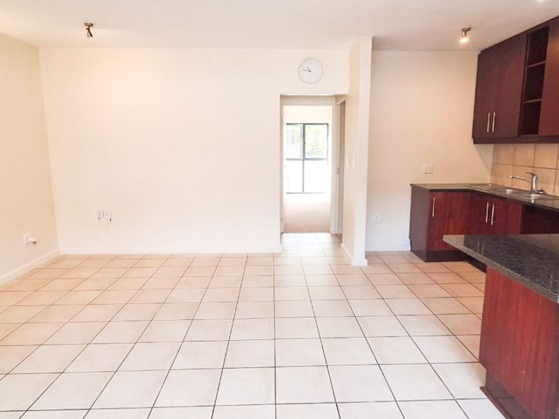 Spacious open-plan living area featuring tiled floors and a functional kitchen with dark wood cabinetry, granite countertops, and built-in appliances.