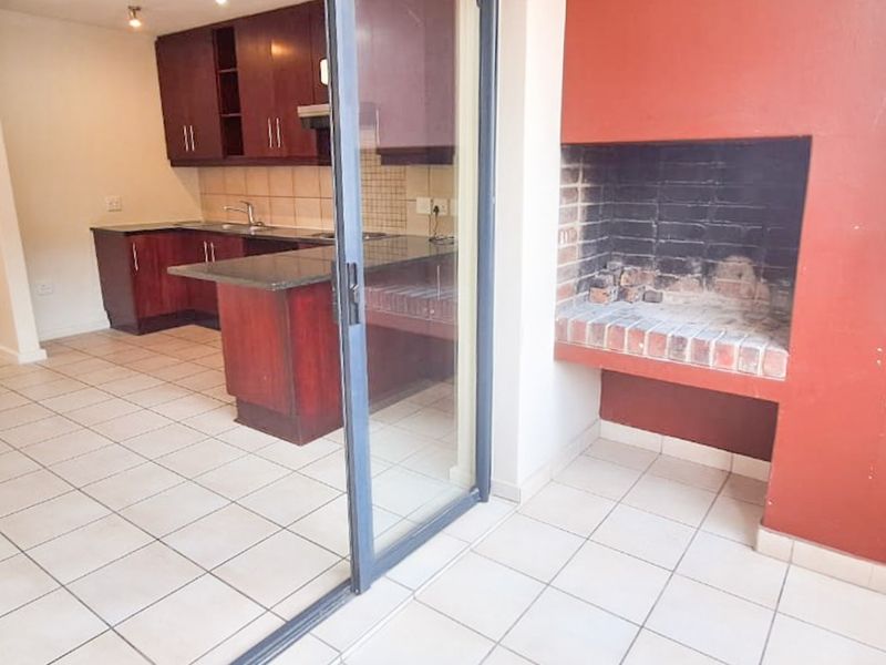 Open plan kitchen area featuring dark wood cabinetry and granite countertops, flowing onto a balcony with a built-in brick braai.