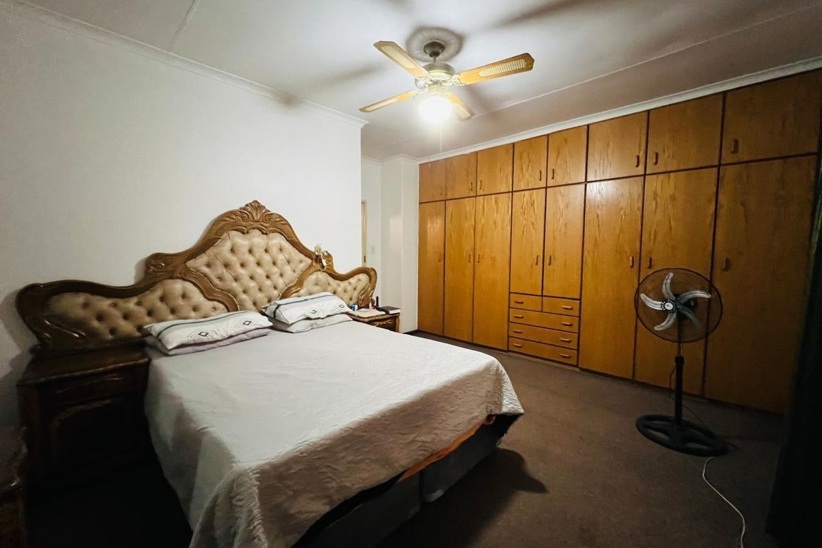 A spacious bedroom featuring extensive wall-to-wall built-in wooden cabinetry and a ceiling fan, offering ample storage space.