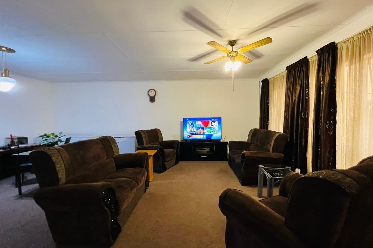 A spacious living room featuring carpeted flooring, a ceiling fan, and coved ceilings, providing a comfortable and functional area for relaxation.