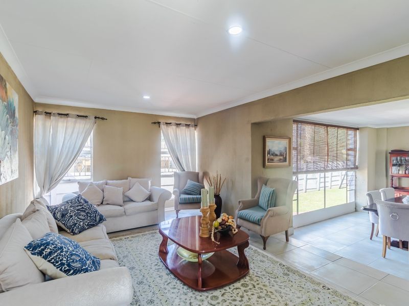 Spacious open-plan living and dining area featuring tiled floors, recessed lighting, and large windows providing natural light and garden views.
