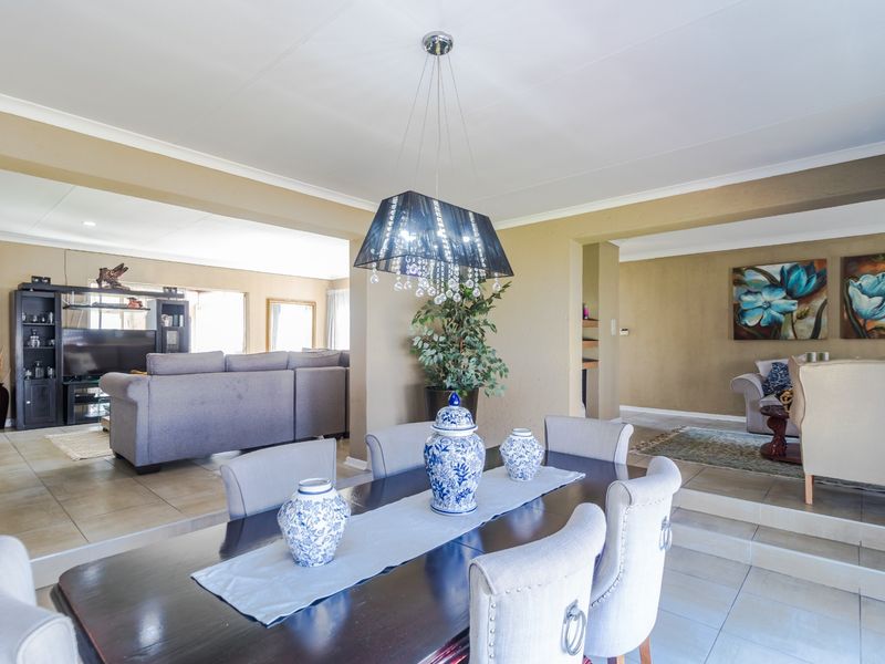 Spacious open-plan dining and living area featuring tiled flooring, a sunken lounge section, and a decorative pendant light fixture.