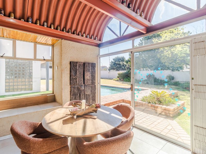 Enclosed patio area featuring a unique vaulted corrugated roof, large sliding glass doors, and direct access to the garden and pool area.