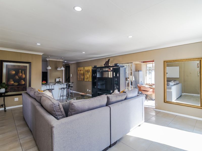 Spacious open-plan living area featuring tiled flooring, recessed downlighting, and a functional kitchen breakfast bar with pendant lighting.