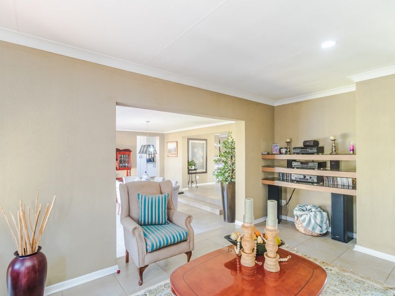 A well-maintained living room featuring tiled flooring, built-in shelving, and a coved ceiling, with an open-plan flow into the adjacent dining area.