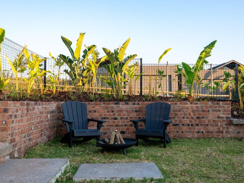 A landscaped garden area featuring a brick retaining wall, wire mesh fencing, and concrete pavers.
