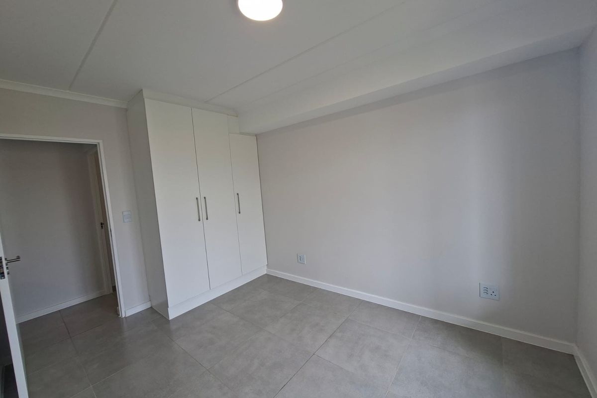 A clean, empty bedroom featuring neutral tiled flooring and modern built-in cupboards, providing a blank canvas for personalization.