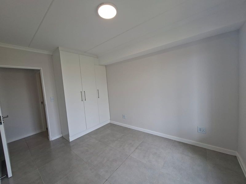A clean, empty bedroom featuring neutral tiled flooring and modern built-in cupboards, providing a blank canvas for personalization.