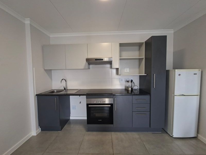 Modern kitchen featuring dark grey and light grey cabinetry, granite countertops, built-in oven, electric hob, extractor fan, and tiled flooring.