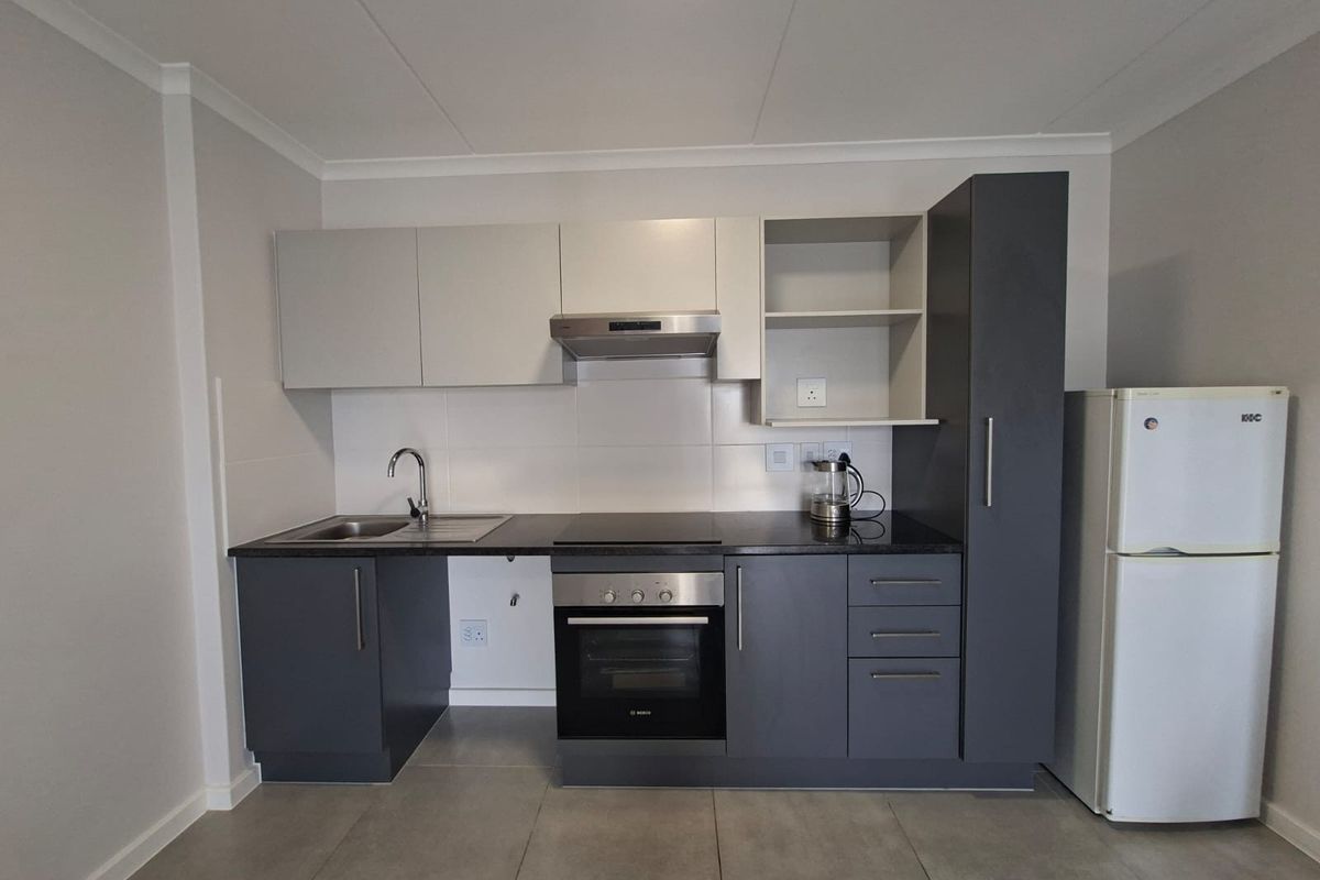 Modern kitchen featuring dark grey and light grey cabinetry, granite countertops, built-in oven, electric hob, extractor fan, and tiled flooring.