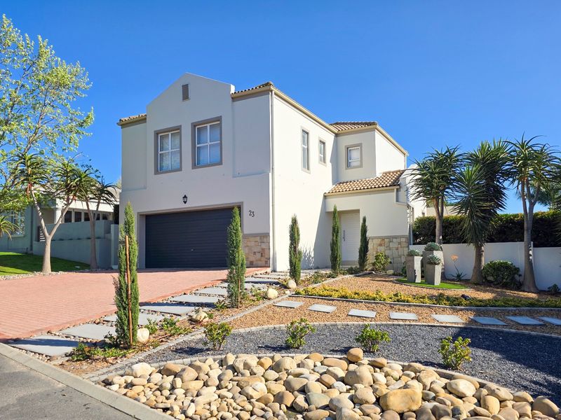 A well-maintained double-story residential home featuring a paved driveway, integrated garage, and neatly landscaped front garden with stone accents.