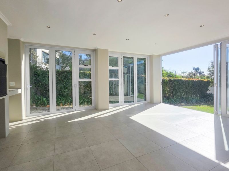 Spacious covered patio featuring large stacking glass doors, tiled flooring, recessed lighting, and a built-in fireplace, offering seamless indoor-outdoor flow.