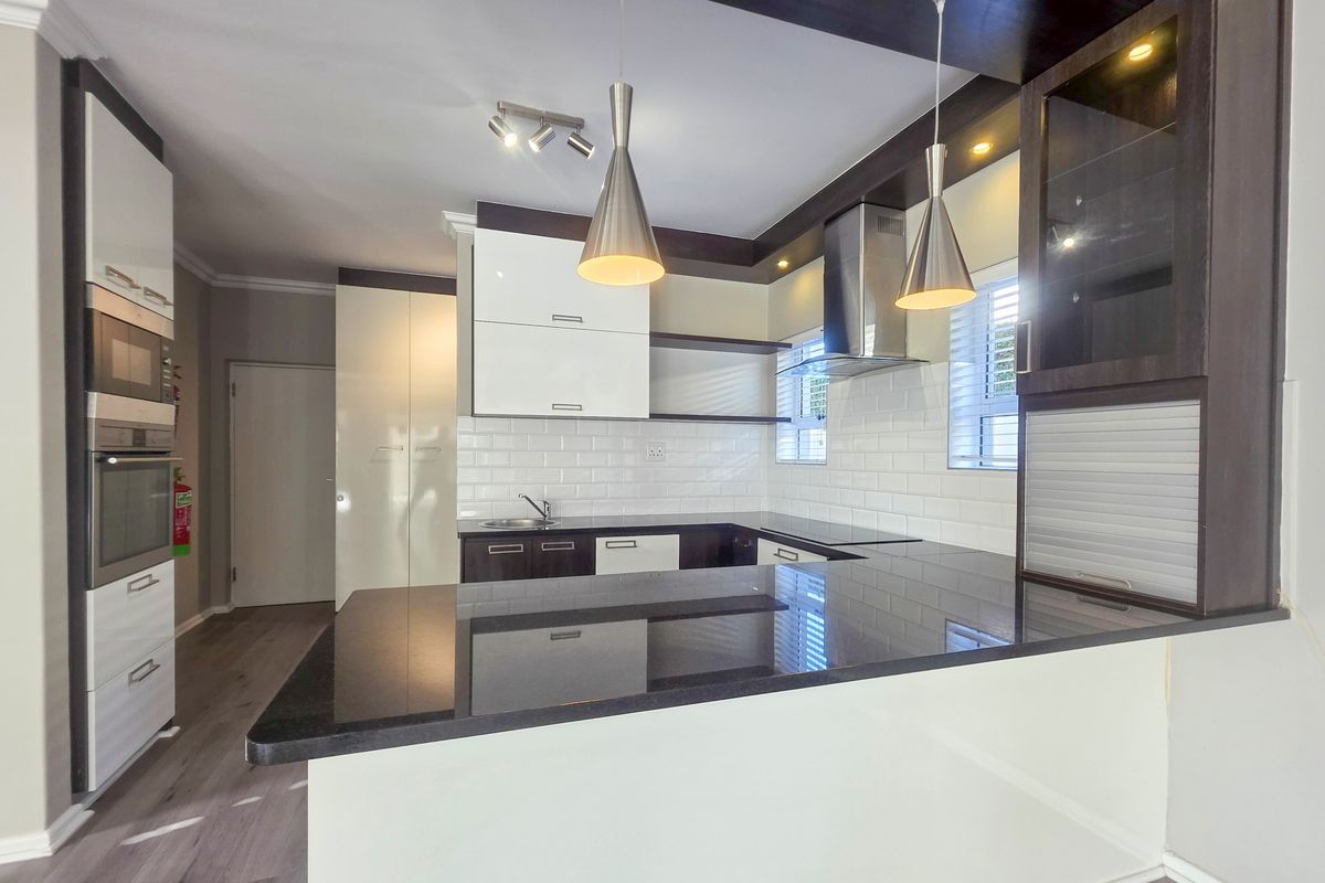 Modern kitchen featuring high-gloss cabinetry, granite countertops, subway tile backsplash, and integrated appliances including an oven, microwave, and extractor fan.