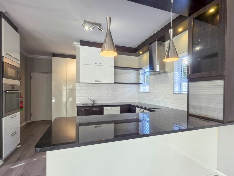 Modern kitchen featuring high-gloss cabinetry, granite countertops, subway tile backsplash, and integrated appliances including an oven, microwave, and extractor fan.