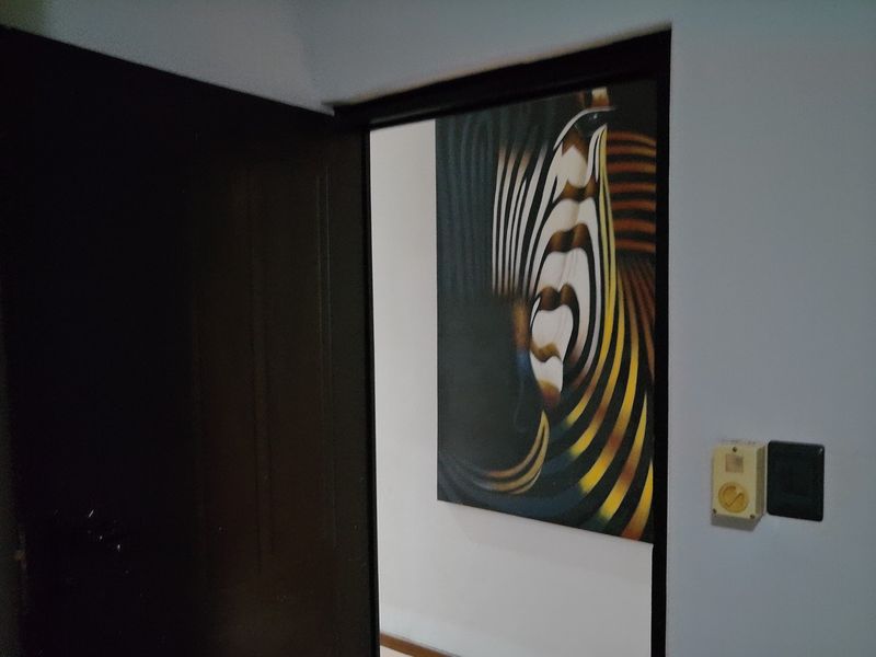 A view through a doorway into a hallway featuring a wall-mounted electrical socket and light switch.