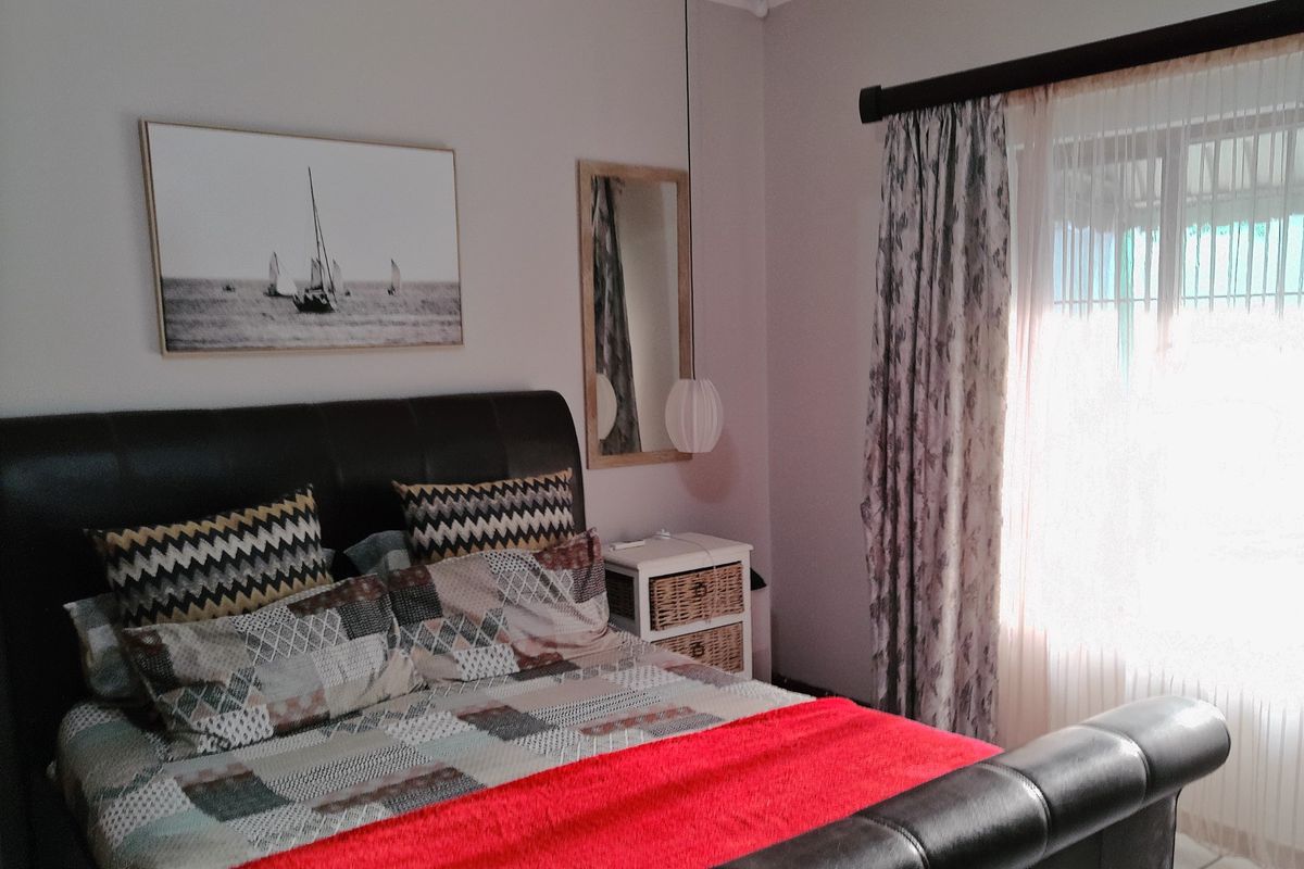 A well-maintained bedroom featuring neutral wall tones, an installed air conditioning unit, and window treatments.