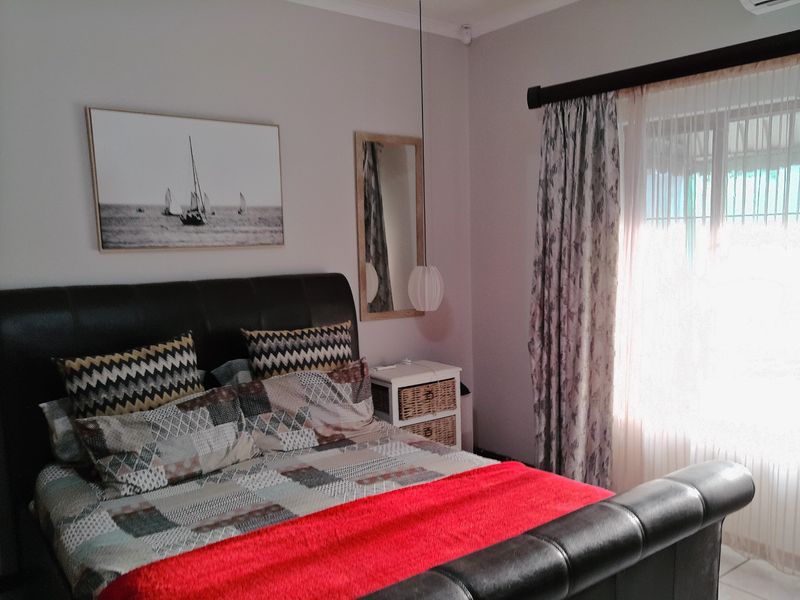 A well-maintained bedroom featuring neutral wall tones, an installed air conditioning unit, and window treatments.