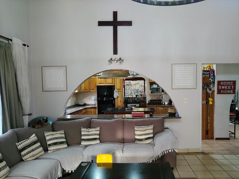 Open plan living area featuring a large arched opening connecting to a functional kitchen with granite countertops and wooden cabinetry.