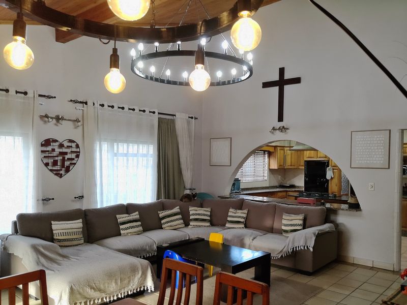 Spacious open-plan living area featuring exposed timber beams, a large arched pass-through to the kitchen, and durable tiled flooring throughout.