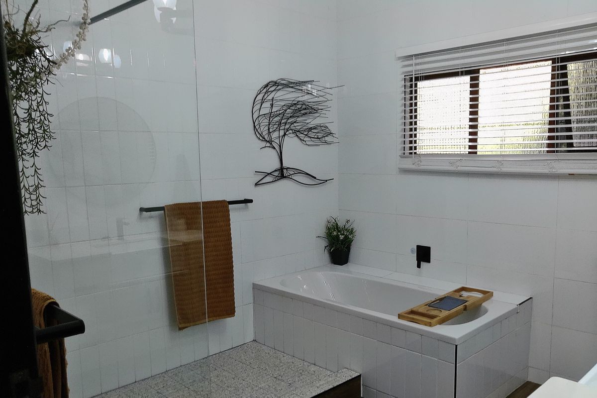A modern bathroom featuring a built-in bathtub, a glass-enclosed shower area, and clean white wall tiling with contemporary fixtures.