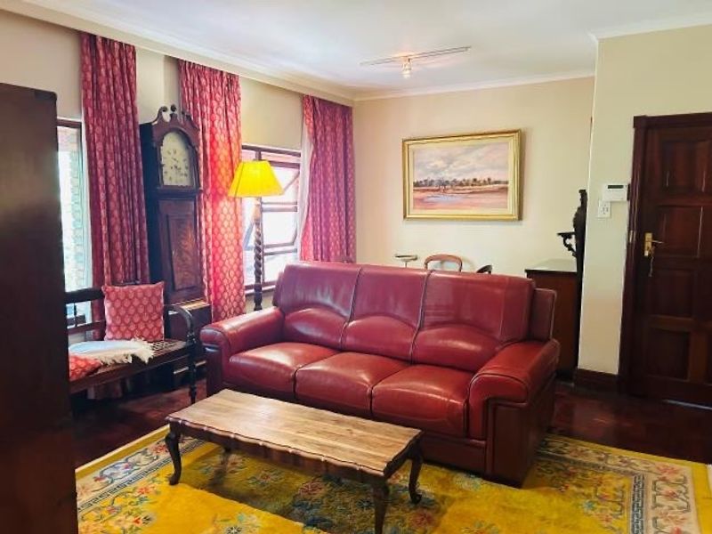 A traditional living room featuring hardwood flooring, coved ceilings, and a solid timber door, offering a classic and well-maintained living space.