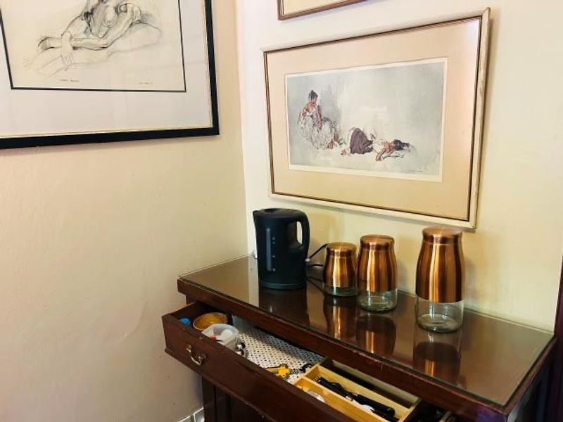 A close-up view of a wooden console table with a glass top, featuring framed artwork on the wall above.
