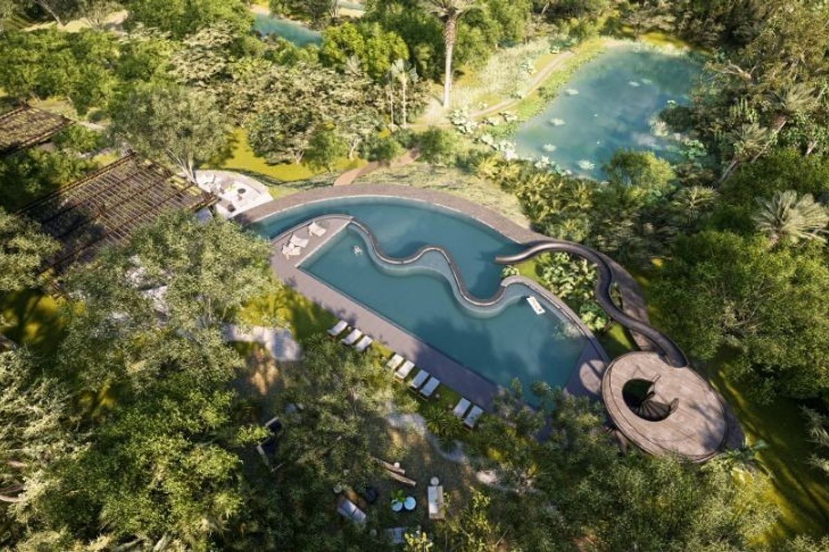 Aerial view of a luxury swimming pool area featuring a water slide, wooden decking, and lush landscaped surroundings.