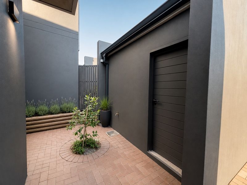 A modern, well-maintained rear courtyard featuring paved flooring, timber slat fencing, and a built-in planter box.