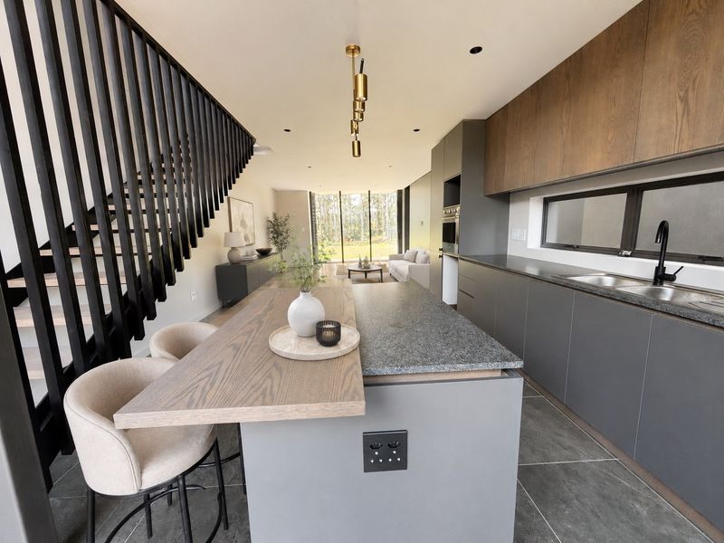 Modern open-plan kitchen featuring sleek grey cabinetry, stone countertops, a central island with breakfast bar, and a striking timber-slat staircase.