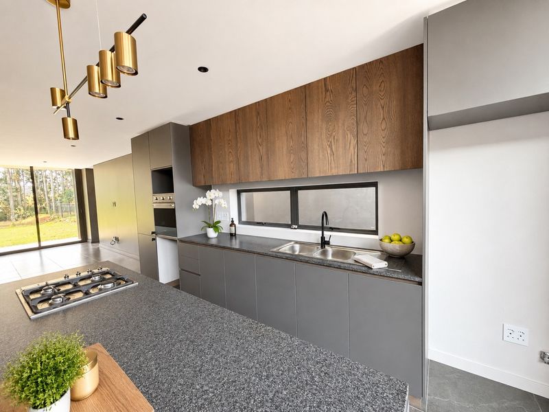 Modern kitchen featuring sleek grey cabinetry, wood-grain upper cabinets, stone countertops, a central island with a gas hob, and high-end integrated appliances.