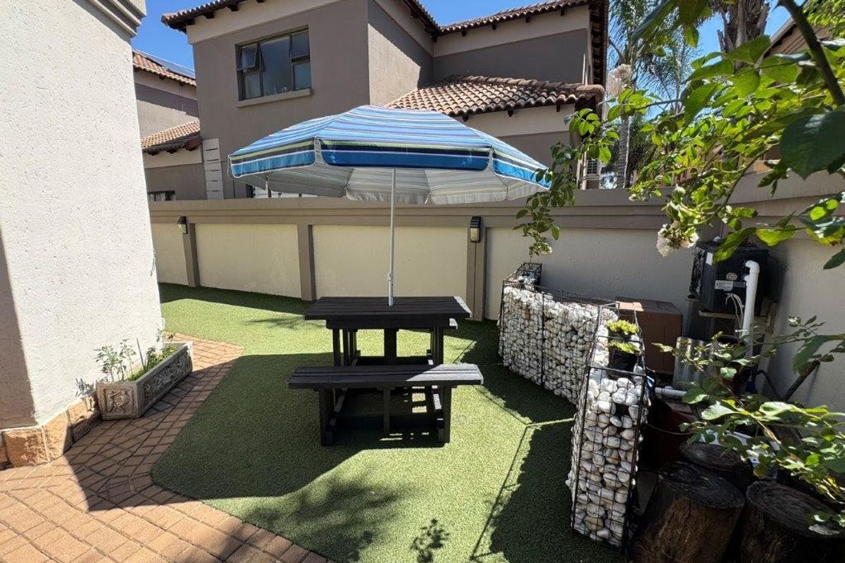 A private rear garden area featuring artificial turf, paved pathways, and decorative gabion walling, providing a low-maintenance outdoor space.