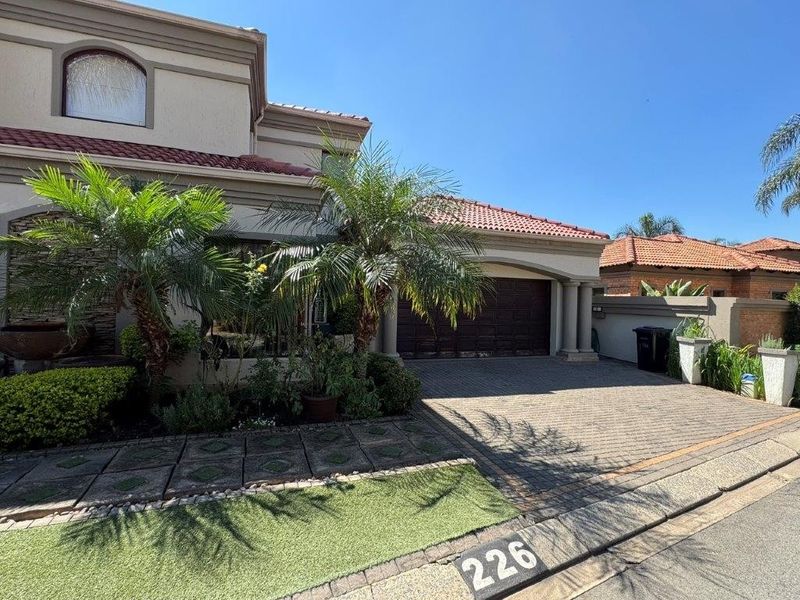 Front elevation of a residential property featuring a paved driveway, double garage, and tiled roof with established landscaping.