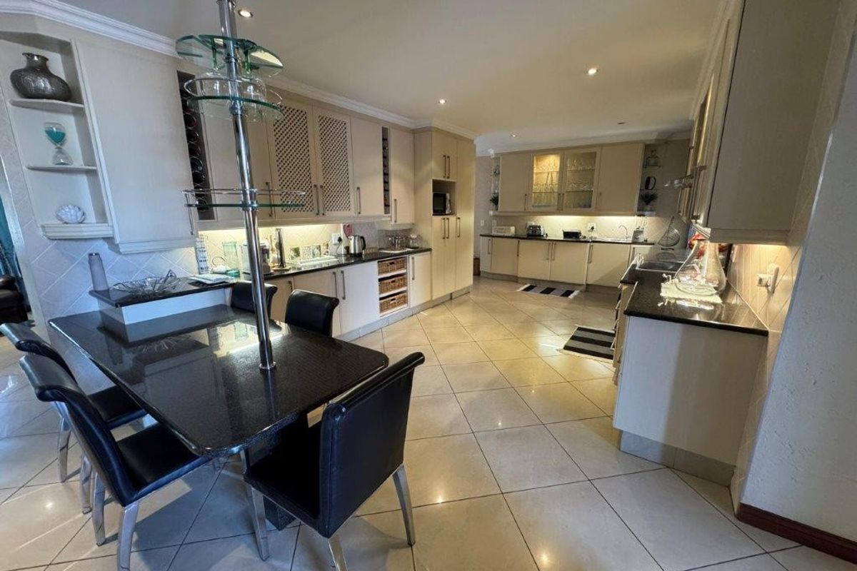 Spacious kitchen featuring extensive built-in cabinetry, granite countertops, and tiled flooring with integrated dining area and recessed lighting.