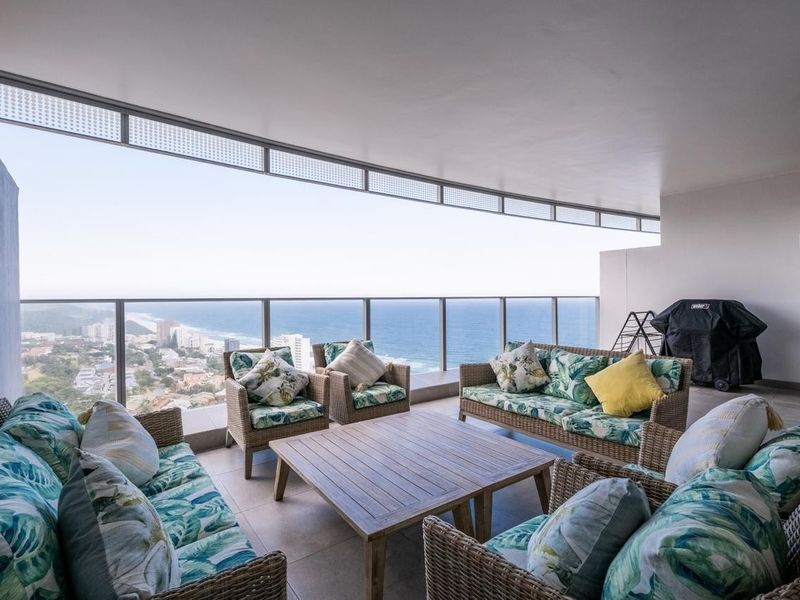 Spacious covered balcony featuring a modern glass balustrade and panoramic ocean views, providing an ideal outdoor entertainment area.