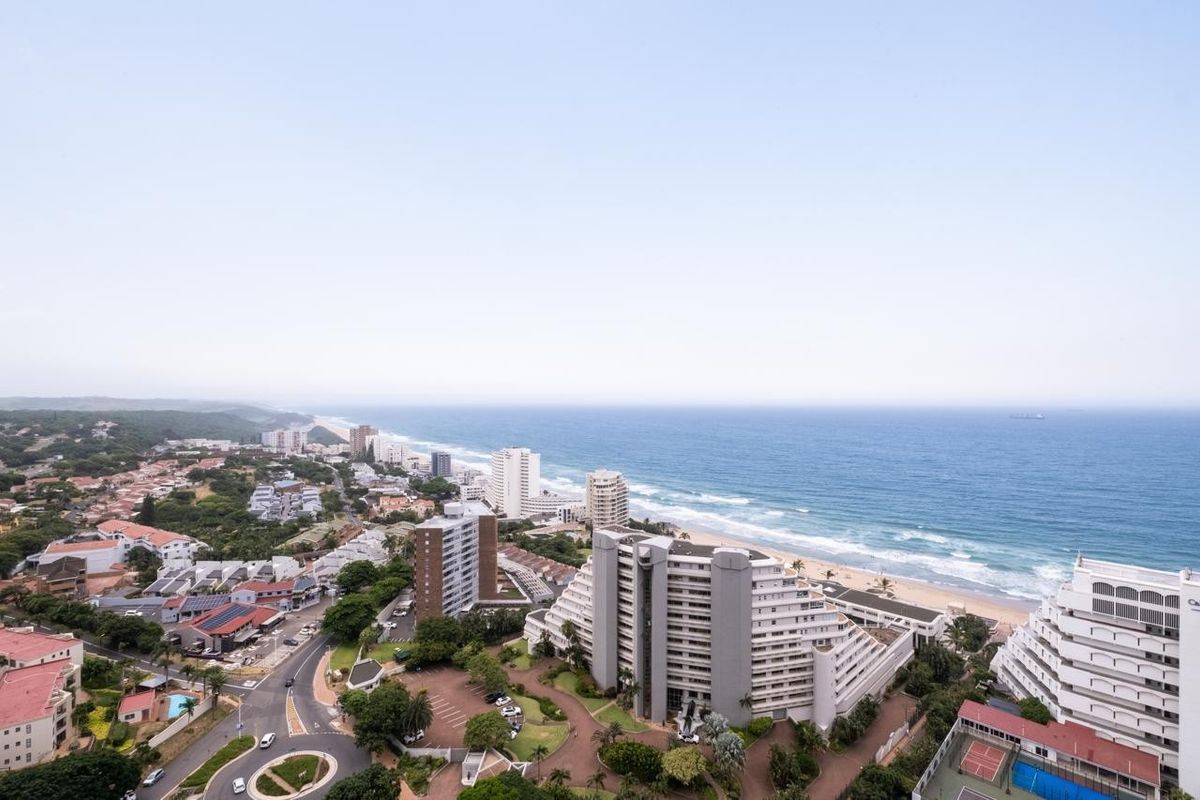 An elevated aerial view showcasing the coastal landscape, surrounding apartment complexes, and proximity to the beach.