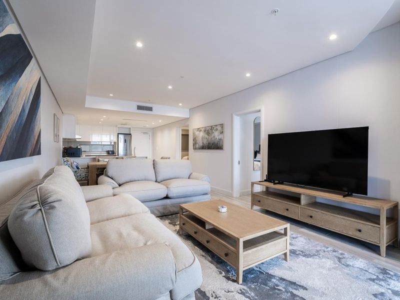 Modern open-plan living area featuring recessed lighting, ducted air conditioning, and a seamless transition to a contemporary kitchen space.