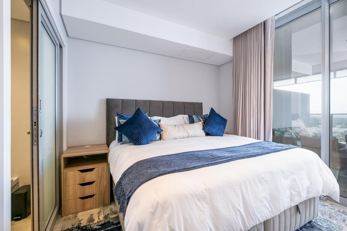 Modern bedroom featuring floor-to-ceiling windows, a sliding glass door, and a clean, contemporary aesthetic with neutral finishes.
