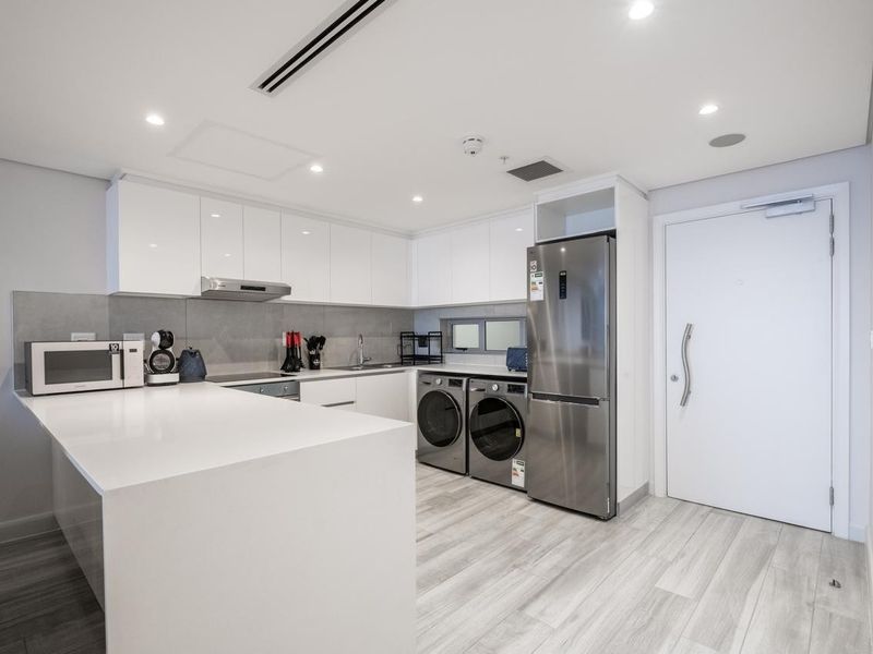 Modern kitchen featuring sleek white cabinetry, stone countertops, integrated appliances, and recessed lighting, offering a clean and functional culinary space.