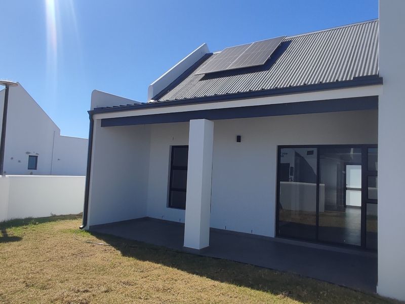 Rear view of the property featuring a covered patio, sliding glass doors, and solar panels installed on the corrugated metal roof.