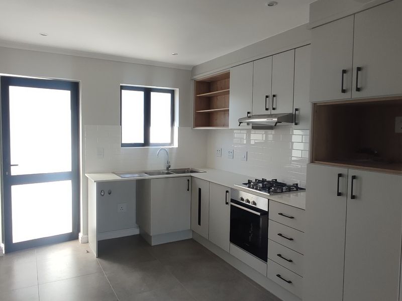 Modern kitchen featuring sleek cabinetry, built-in gas hob, electric oven, extractor fan, subway tile backsplash, and tiled flooring with direct outdoor access.
