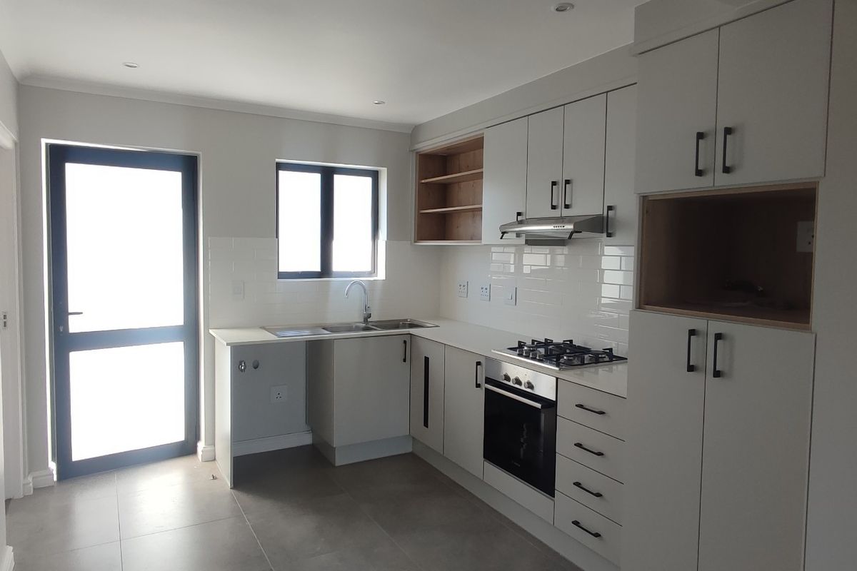 Modern kitchen featuring sleek cabinetry, built-in gas hob, electric oven, extractor fan, subway tile backsplash, and tiled flooring with direct outdoor access.