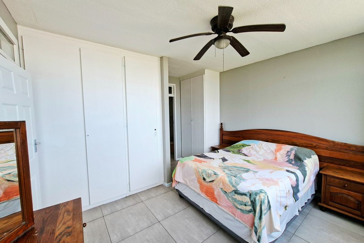 A bedroom featuring tiled flooring, a ceiling fan, and extensive built-in cupboard storage.
