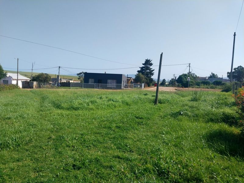 A view of a vacant residential plot featuring a grass lawn, perimeter fencing, and utility poles, situated in a residential neighborhood.