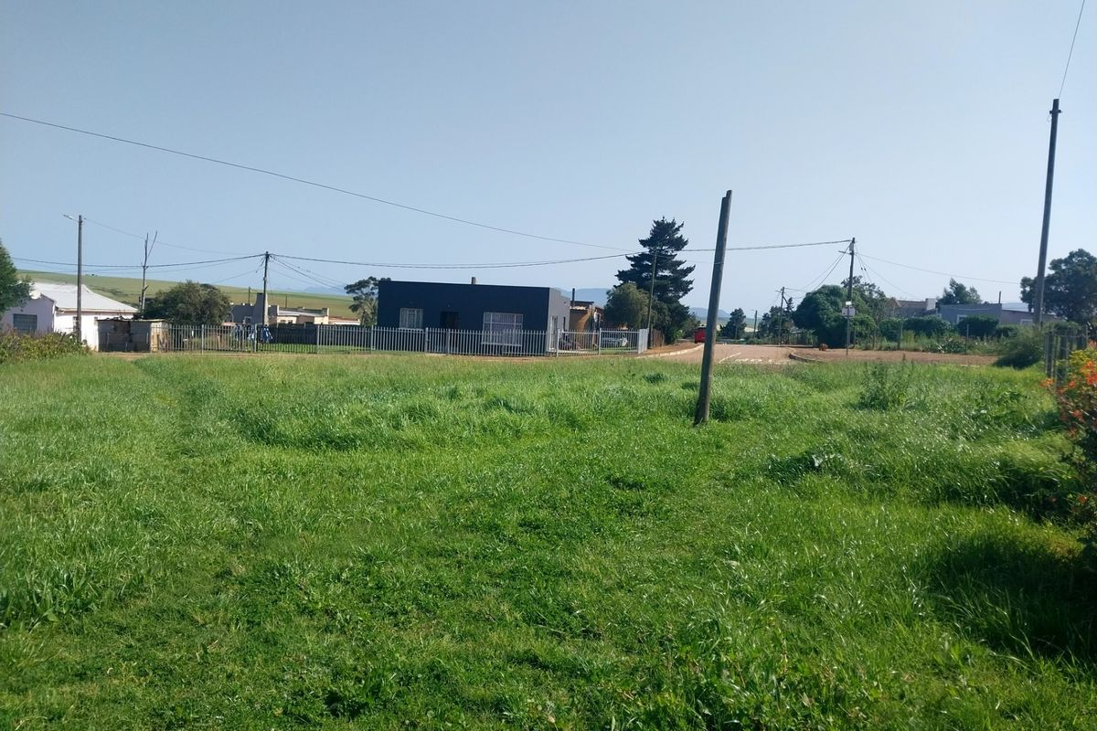A view of a vacant residential plot featuring a grass lawn, perimeter fencing, and utility poles, situated in a residential neighborhood.