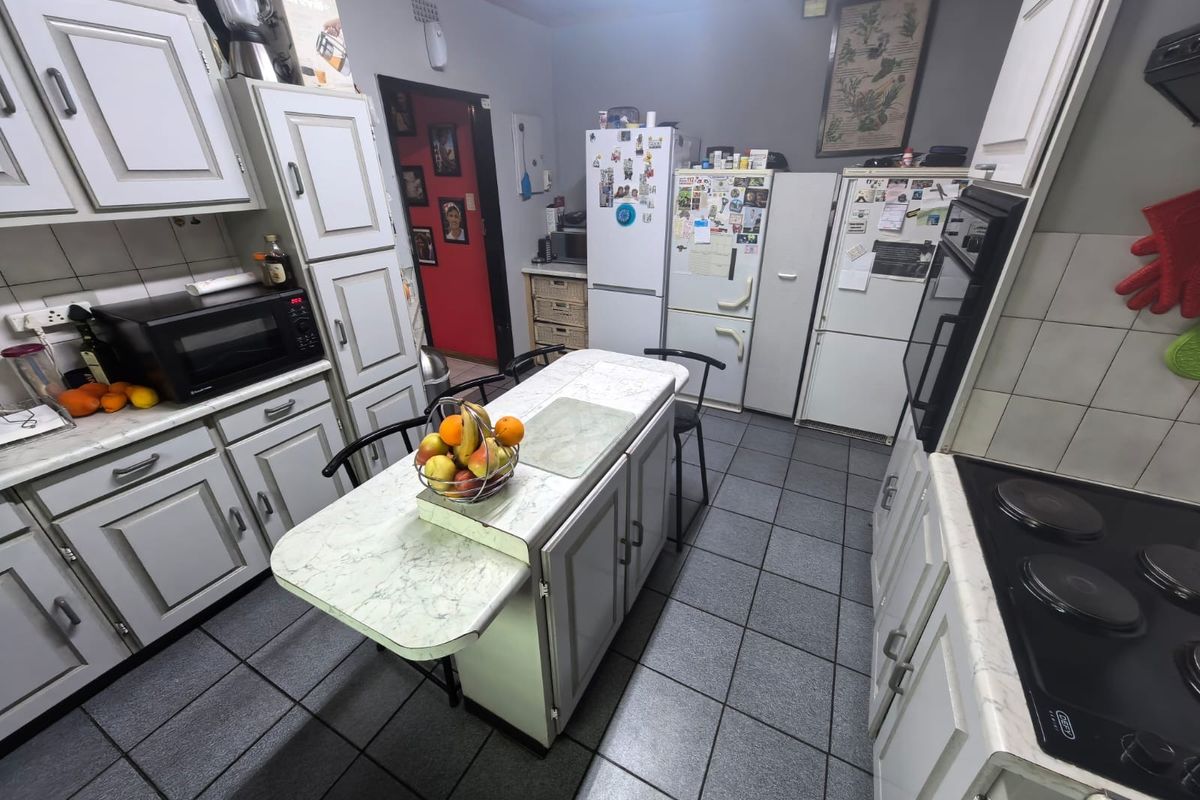 A functional kitchen featuring built-in cabinetry, tiled flooring, and integrated appliances, offering a practical layout for daily meal preparation.