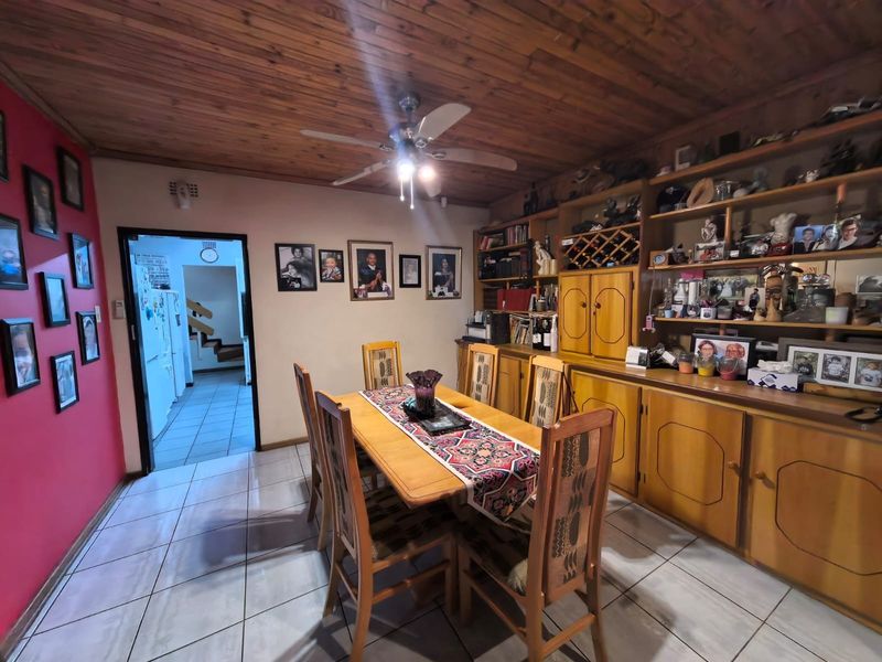 Dining room featuring timber ceiling, ceiling fan, tiled flooring, and extensive built-in wooden cabinetry for storage and display.