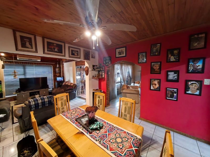 Open-plan living and dining area featuring a timber ceiling, ceiling fan, tiled flooring, and an air conditioning unit, with an arched transition to adjacent spaces.