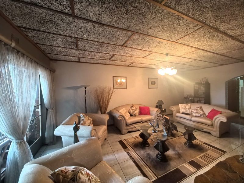 Spacious living room featuring tiled flooring and a distinctive textured acoustic ceiling, with direct access to the outdoor area through a sliding glass door.